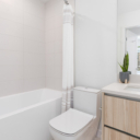 Bathroom at Avenue 33 by Vertex Developments featuring a bathtub, one-piece dual flush DURAVIT toilet, solid surface quartz countertops, porcelain tile flooring, and a floating vanity mirror.