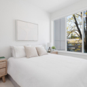 Bedroom at Avenue 33 by Vertex Developments featuring a large 3-panel exterior window and plush wool blend carpeting, with staged furniture.