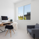 Flex room setup as a den at Avenue 33 by Vertex Developments featuring plush wool blend carpeting and a 2-panel exterior window, with staged furniture.