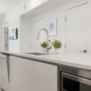 Kitchen island at Avenue 33 by Vertex Developments featuring integrated dishwasher with door slightly ajar, showcasing modern kitchen design.